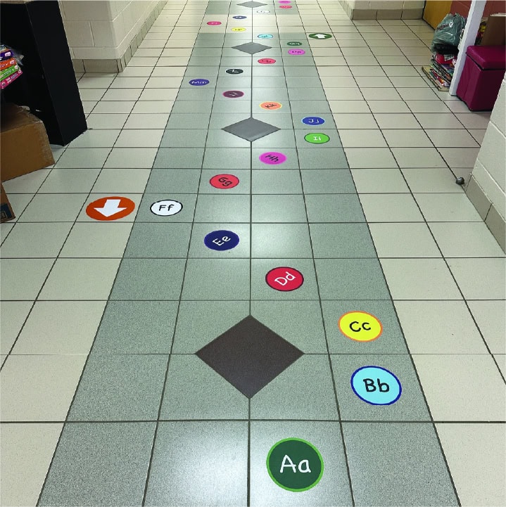 Colorful sensory path with numbered and lettered circles on tiled floor.