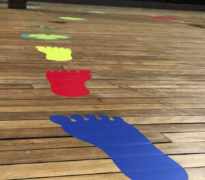 Colorful sensory path footprints on wooden floor for children.